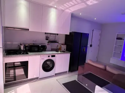 a kitchen with white cabinets and a washing machine at Alojamento Ribeirinha in Mindelo