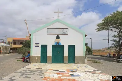 a small white church with green doors and a cross at Tity Apartments T2 in Santa Maria