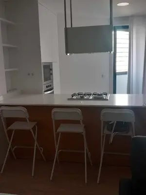 a kitchen with a counter with three chairs and a stove at Rita Apartamento in Mindelo