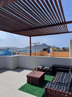 a patio with a couch and a table on a roof at Sunset in Mindelo
