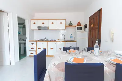 a dining room with a table with chairs and a kitchen at Soleado 9 in Santa Maria