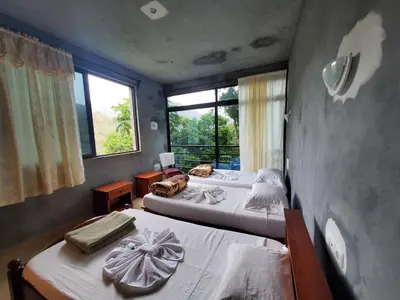 two beds in a room with two windows at Puntinha d'Djô in Caculi