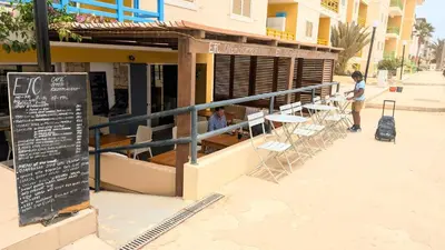 a woman standing in front of a restaurant with tables and chairs at Turtle Apart in Sal Rei