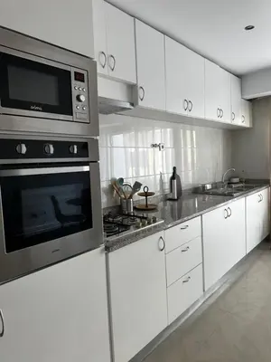 a kitchen with white cabinets and a microwave at Fanon Flat T2 in Mindelo