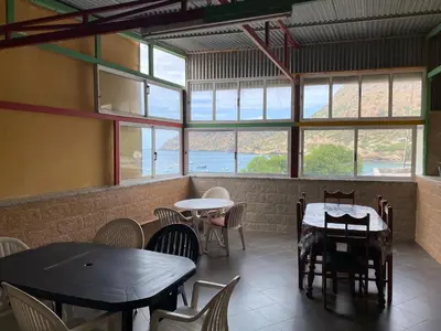 a restaurant with two tables and chairs and windows at Tarrafal Paradise Suite in Tarrafal