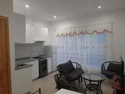a kitchen and a living room with a table and chairs at Ap ACVA in Mindelo