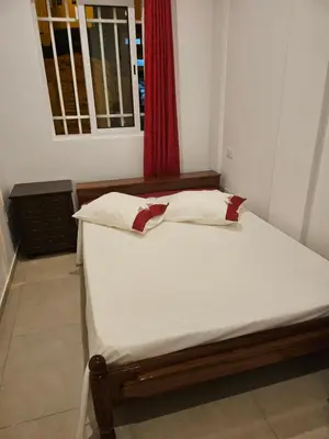 a bed in a room with a red window at Ap ACVA in Mindelo
