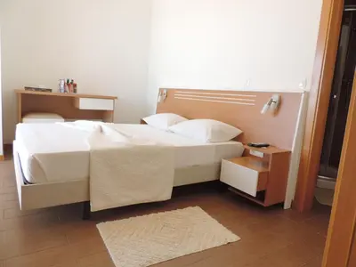 a bedroom with a white bed and a night stand at Hotel Halcyone - Ilha do Maio in Calheta Do Maio