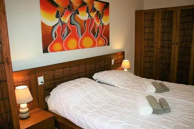 a bedroom with a bed with two towels and a painting at African Lounge, Moradias Laranja in Prainha