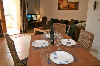a dining room table with a bottle of wine on it at African Lounge, Moradias Laranja in Prainha