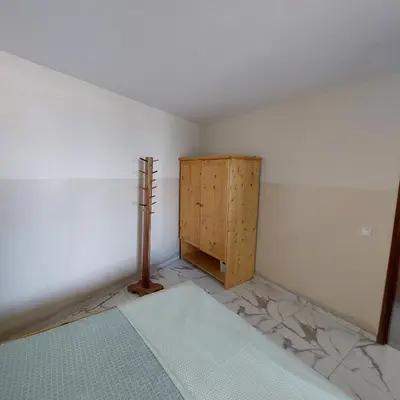 a bedroom with a bed and a wooden cabinet at Oia Mindelo Chambre d'hotes in Mindelo