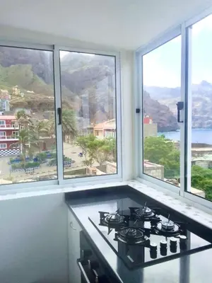 a kitchen with a stove and three windows with a view at Oásis de retour in Ponta do Sol