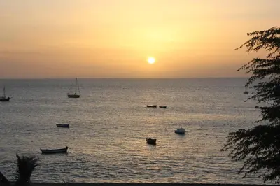 a group of boats in the water at sunset at Joli et fonctionnel proche centre et plage in Vila do Maio