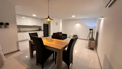 a dining room table with black chairs and a kitchen at Duarte Apartments - Império in Mindelo
