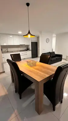 a dining room table with black chairs and aendant light at Duarte Apartments - Império in Mindelo