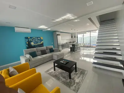 a living room with yellow furniture and a staircase at Mendes Guesthouse in Tarrafal