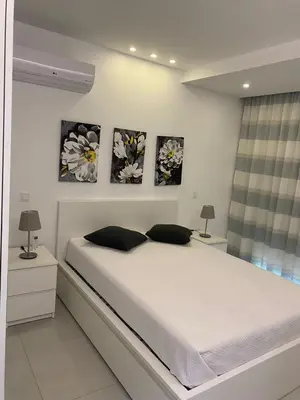 a bedroom with a bed with three paintings on the wall at Mendes Guesthouse in Tarrafal