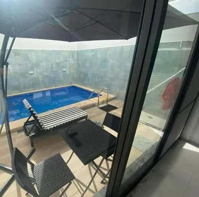 a balcony with a table and chairs and a swimming pool at Mendes Guesthouse in Tarrafal