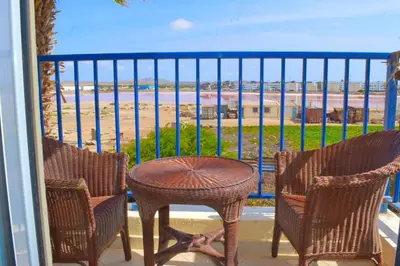 a balcony with a table and chairs and a view of the beach at Suíte Salinas - Vila Cabral 2 in Sal Rei