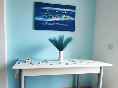 a white table in a room with a painting on the wall at Onda do Mar in Santa Maria