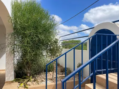 a blue staircase with a plant next to a building at Magnifique villa avec piscine privée à 300m de la plage in Vila do Maio