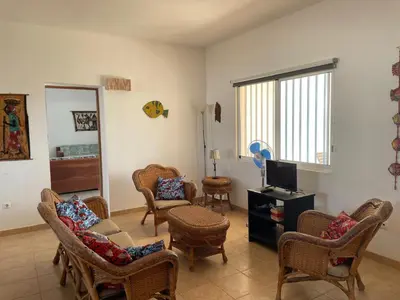 a living room with wicker chairs and a tv at Magnifique villa avec piscine privée à 300m de la plage in Vila do Maio