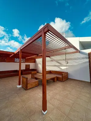a pavilion with wooden benches on a roof at Magnifique villa avec piscine privée à 300m de la plage in Vila do Maio