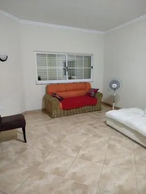 a living room with an orange couch and a window at Apartamento espaçoso de 2 quartos amplos e mobilados in Praia