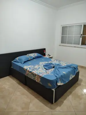 a bed with a blue comforter in a bedroom at Apartamento espaçoso de 2 quartos amplos e mobilados in Praia