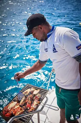 a man cooking food on a grill on a boat at Privat Apartment with Pool View! in Santa Maria