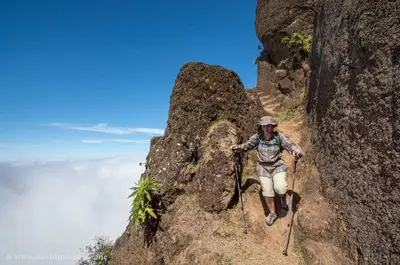 a man walking up a mountain on trekking poles at Oiá Paúl in Paul