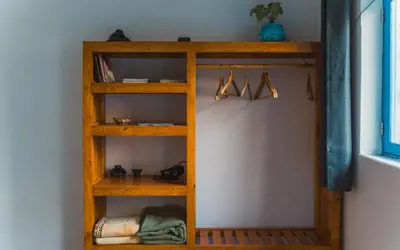 a wooden book shelf with hangers in a room at Oiá Paúl in Paul