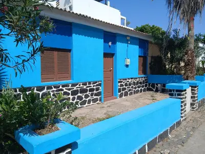 a blue house with a blue bench in front of it at Mille Nuits Appartement in Tarrafal