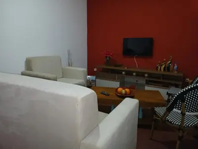 a living room with a white couch and a tv at Mille Nuits Appartement in Tarrafal