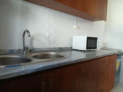 a kitchen counter with a sink and a microwave at Mille Nuits Appartement in Tarrafal