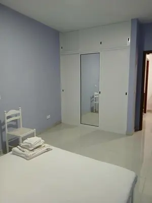 a white room with a bed and a chair at Cozy Maia in Mindelo