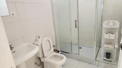 a white bathroom with a toilet and a shower at Please Read Email-Free EARLY Check In & Out-No Walk-Ins or Cash Accepted-Meeting Point Hostels in São Filipe