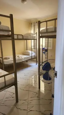 a room with three bunk beds in a room with a tile floor at Please Read Email-Free EARLY Check In & Out-No Walk-Ins or Cash Accepted-Meeting Point Hostels in São Filipe