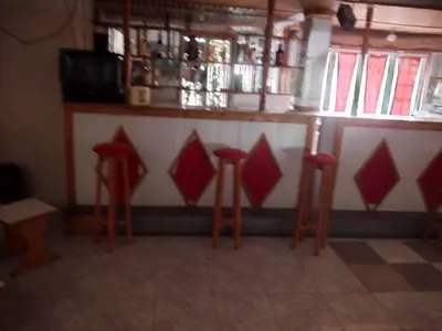 a bar with four red stools in a room at Bar Residencial Frontera in Mindelo