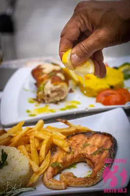 a person is squeezing a lemon on a plate of food at Prassa 3 Boutique Hotel in Mindelo