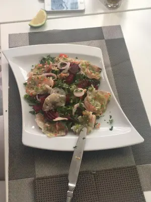 a plate with a salad on a table with a knife at Prassa 3 Boutique Hotel in Mindelo