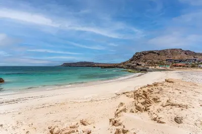 a sandy beach with the ocean and a mountain at Barceló Marine Boa Vista - Adults Only in Sal Rei