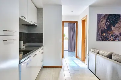 a kitchen with white cabinets and a painting on the wall at Apartamento Ap3 T1 Santa Maria Residence in Santa Maria