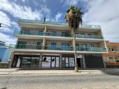 a building with a palm tree in front of it at Apartamento Ap3 T1 Santa Maria Residence in Santa Maria