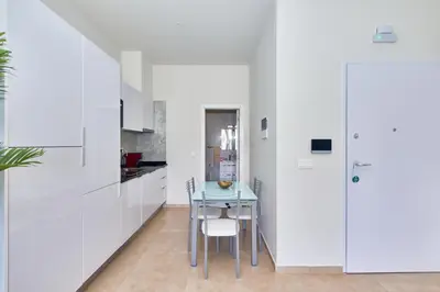 a kitchen with white walls and a table and chairs at Apartamento Praia Santa Maria in Santa Maria