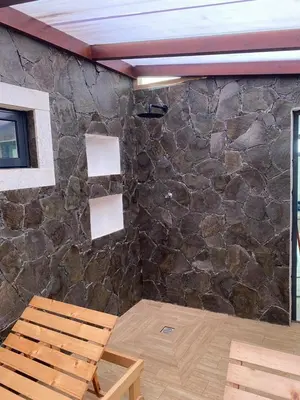a room with a stone wall and a wooden chair at Beach House in Calhau