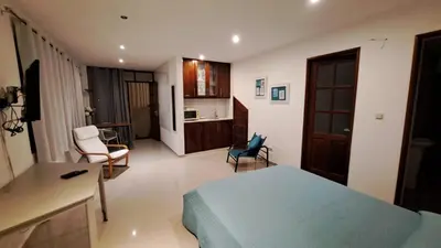 a bedroom with a bed and a desk and a kitchen at Studio Cruz Espia in Mindelo