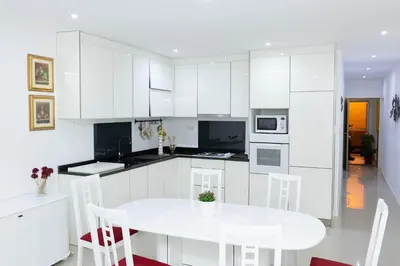 a white kitchen with a white table and chairs at Casa kretcheu Mindelo in Mindelo