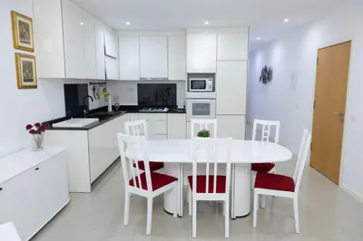 a white kitchen with a white table and chairs at Casa kretcheu Mindelo in Mindelo