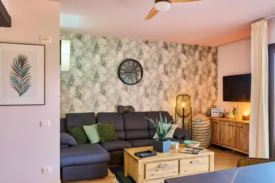 a living room with a couch and a clock on a wall at Tropical Manera in Santa Maria